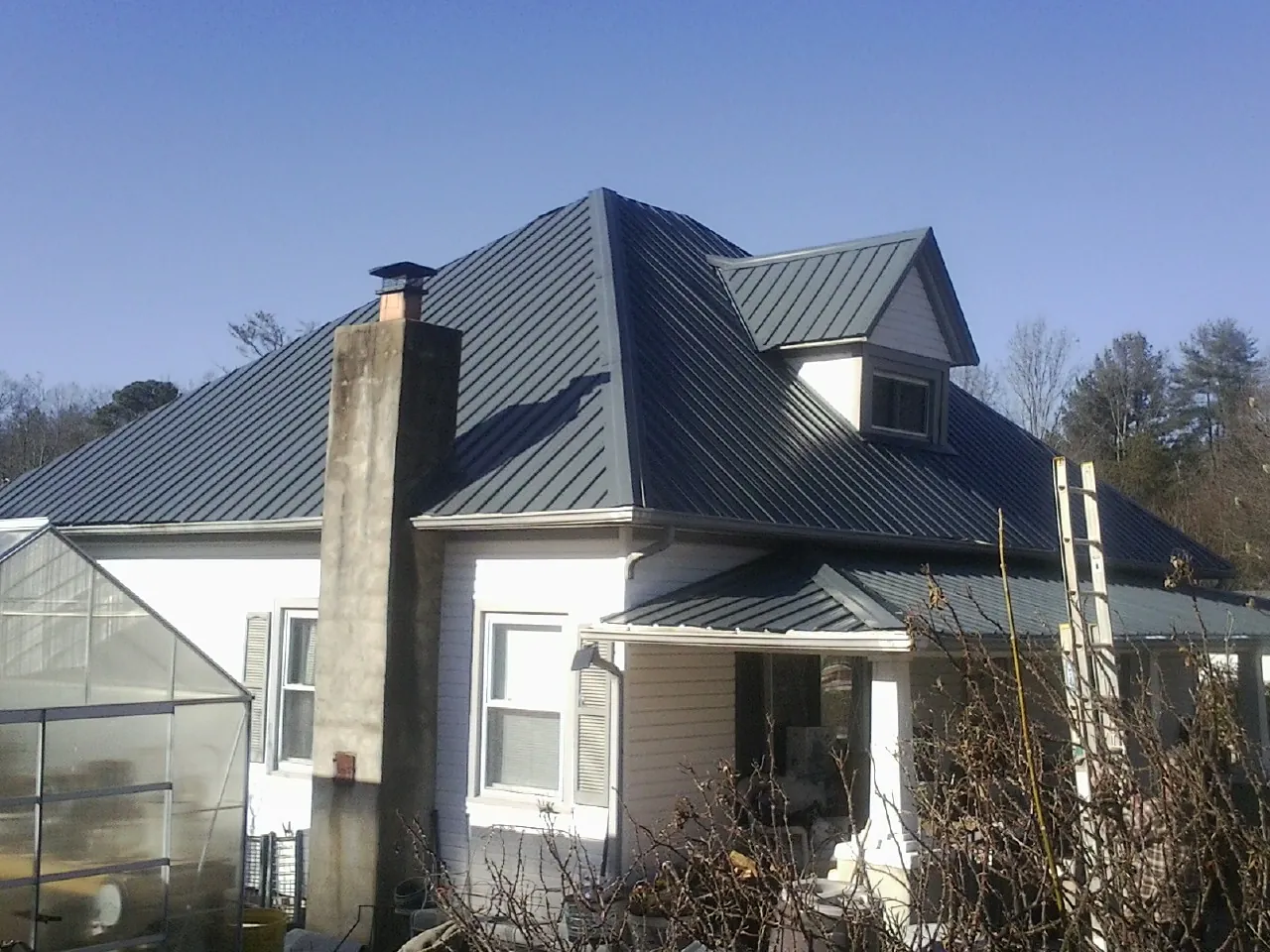 Dark blue standing seam metal roof on a white farmhouse with dormer — Slate & Tile Roof Repair by Roofing Brothers in Yeagertown