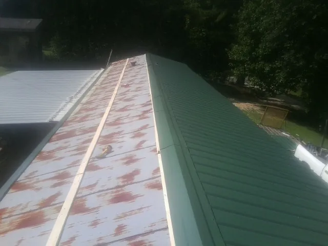 Old rusted panels beside newly installed green metal roofing — Wind Damage Roof Repair by Roofing Brothers in Yeagertown
