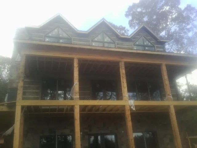 Dormers and porch framing on a large log home under construction — Roof Coating work by our crew in Yeagertown