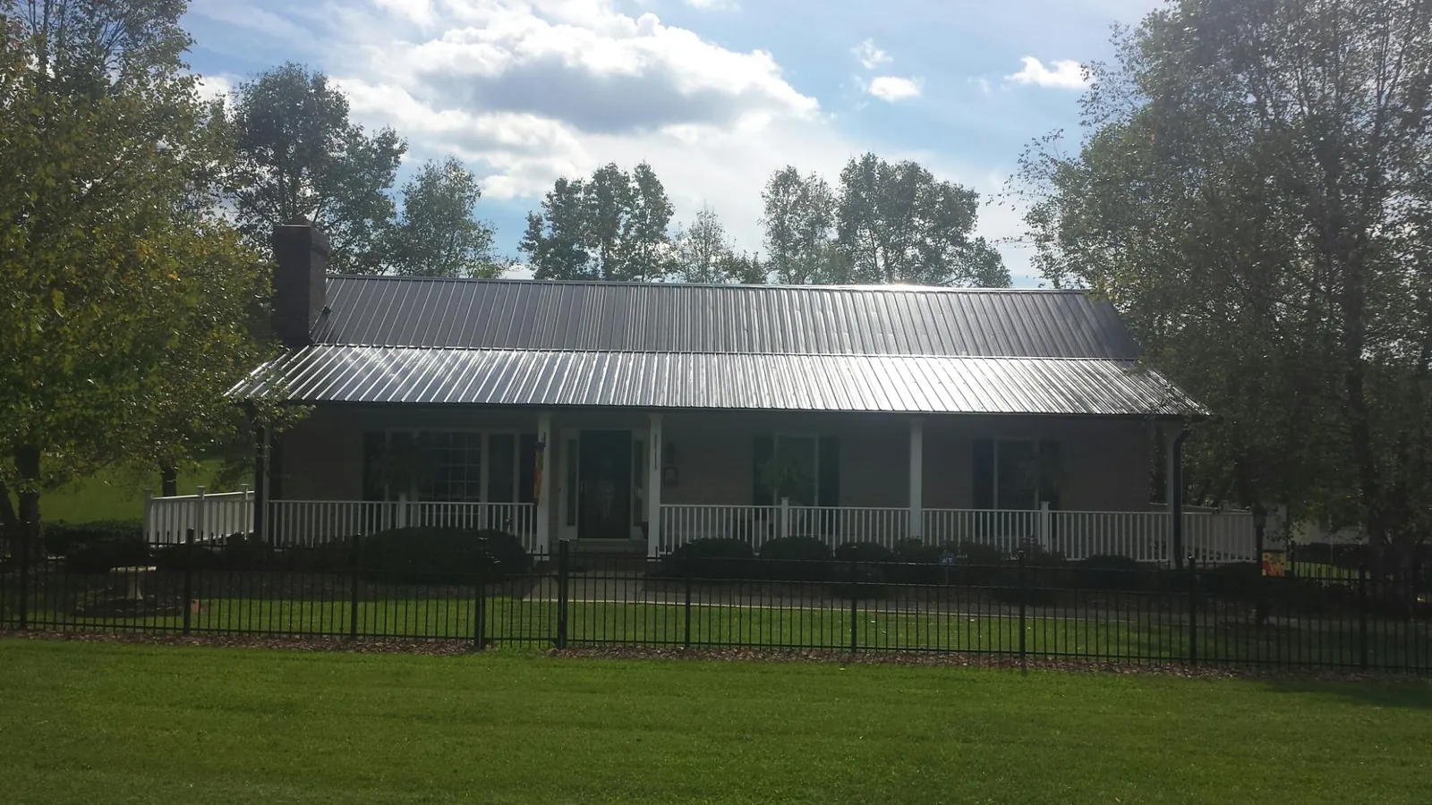 Gray metal roof on a brick ranch with a full width front porch — Gutter Guard Installation work by our crew in Yeagertown