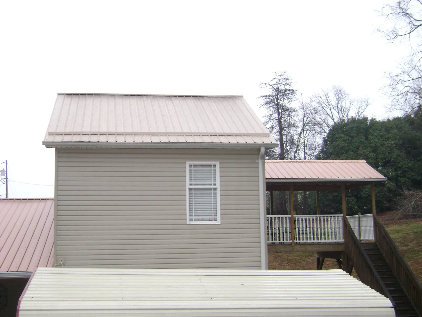 Tan metal roofs on a two story addition and attached porch, from a Roof Replacement job in Yeagertown