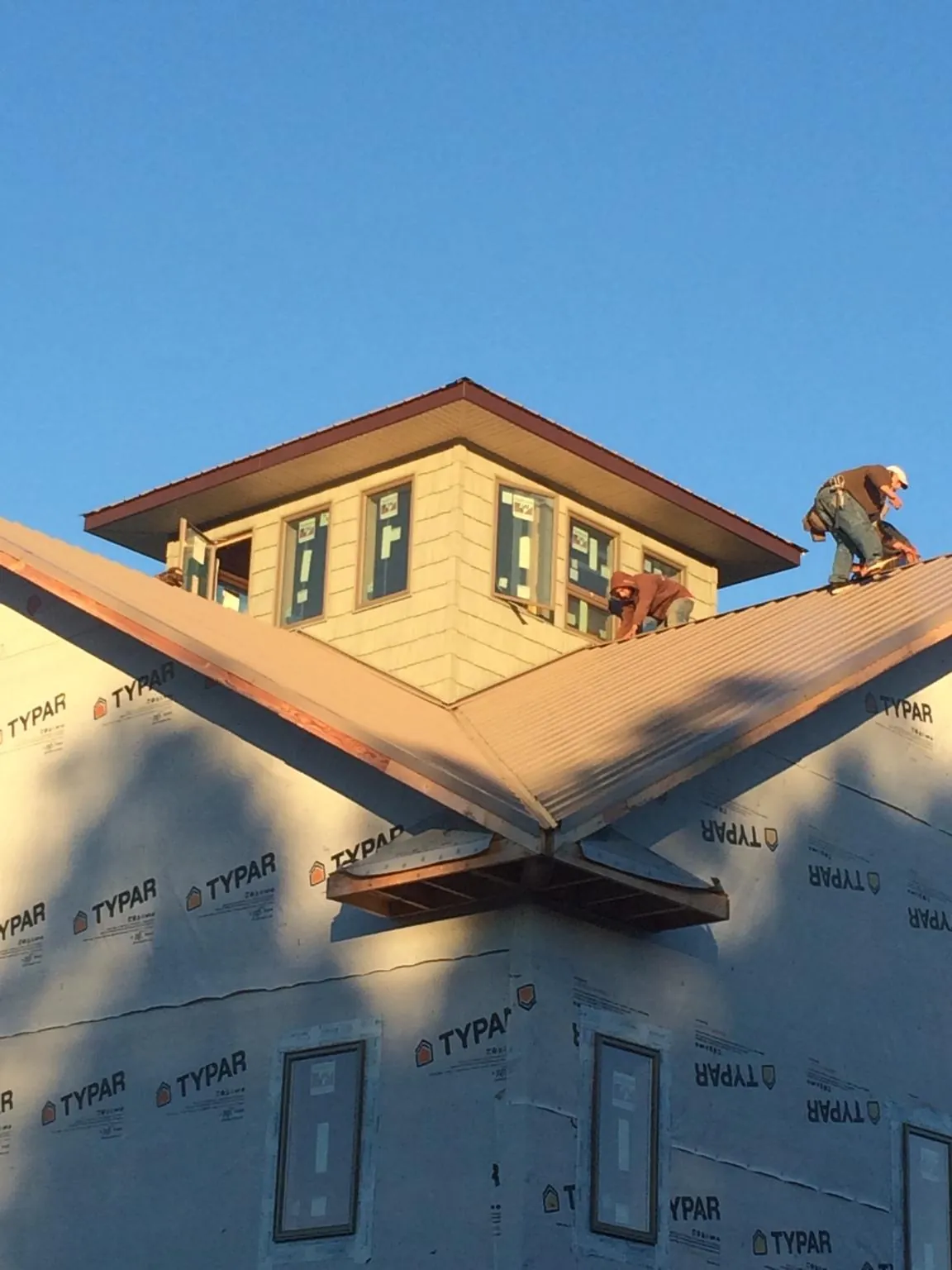 Roofers working around a rooftop cupola on a new metal roof at sunset — Roof Waterproofing in Yeagertown by Roofing Brothers